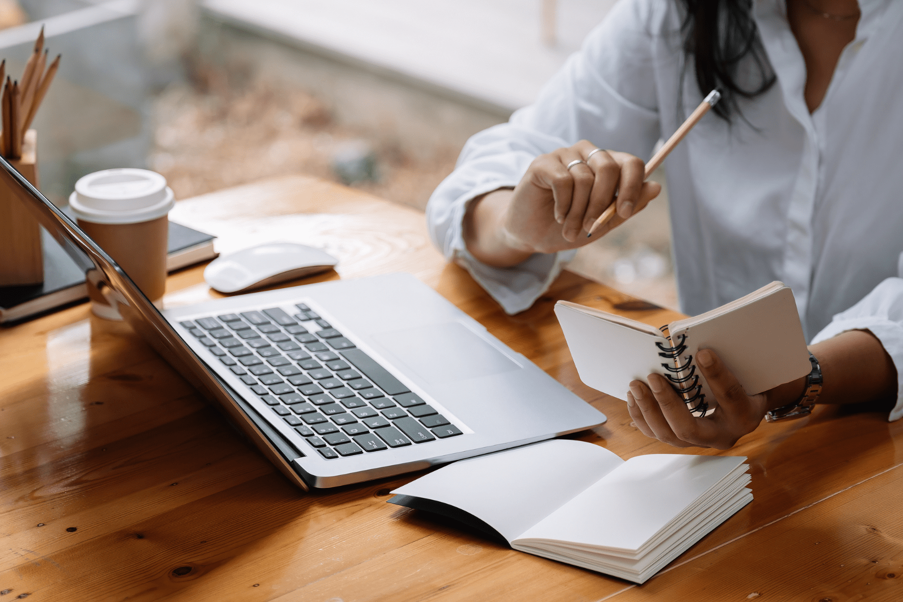Flex Desk im Coworking Space man sieht einen Laptop, Schreibunterlagen und einen Coffee to go